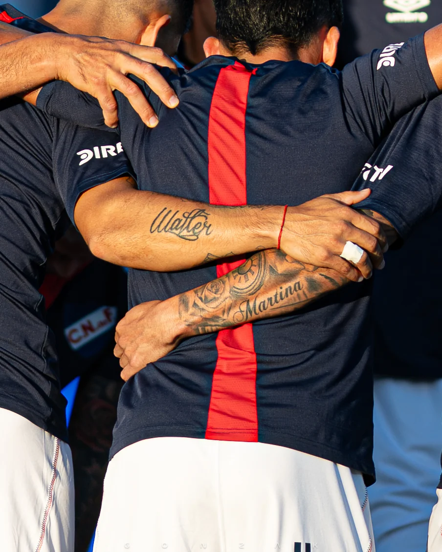 Detalle de brazos y manos en un abrazo entre compañeros.